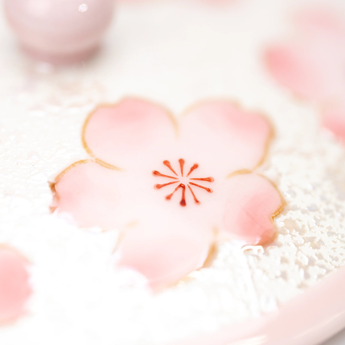 Close-up of a pink flower and pale textured decoration on the teacup.