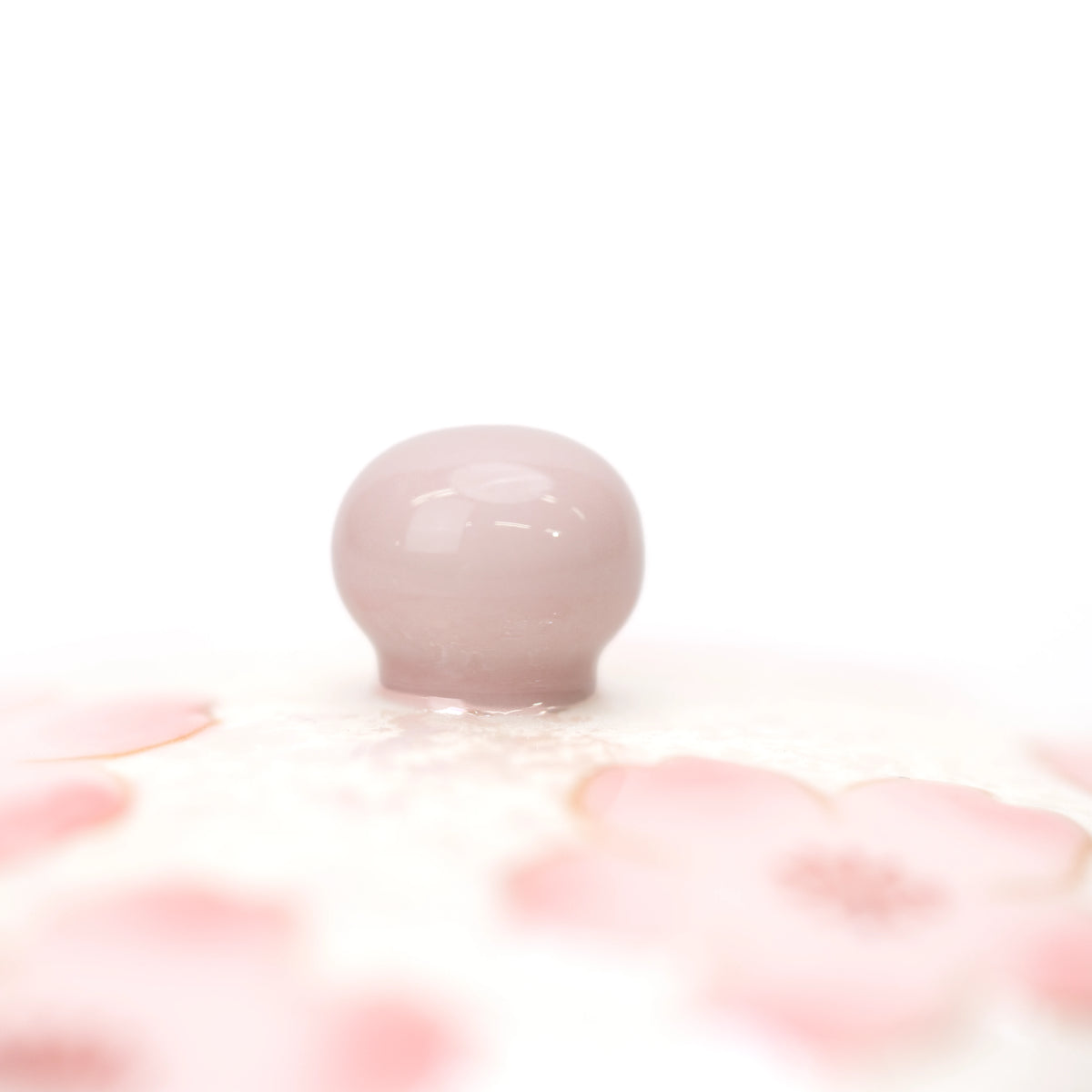 Rounded pink knob on the cherry blossom lid.