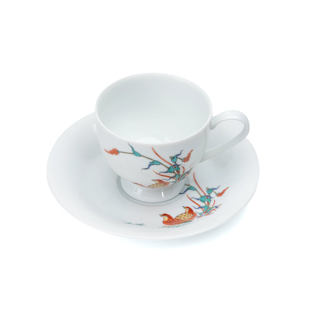 Overhead view of the porcelain cup and saucer with quail and red berries.