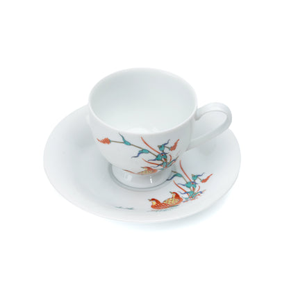 Overhead view of the porcelain cup and saucer with quail and red berries.