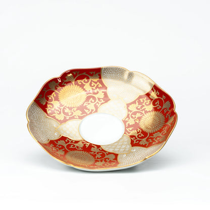 Red and gold scalloped saucer viewed from above.