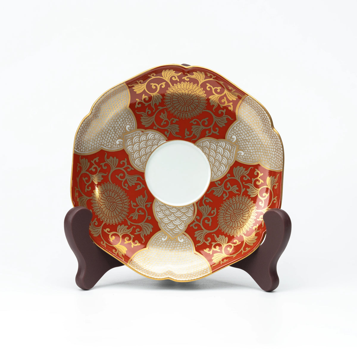 Red and gold saucer displayed upright on a small stand.