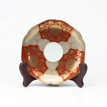 Red and gold saucer displayed upright on a small stand.