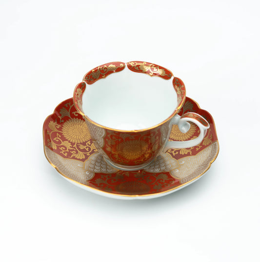 Red and gold chrysanthemum cup and scalloped saucer on white.