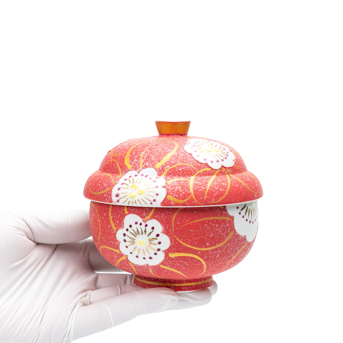 Red floral lidded bowl held in a gloved hand.