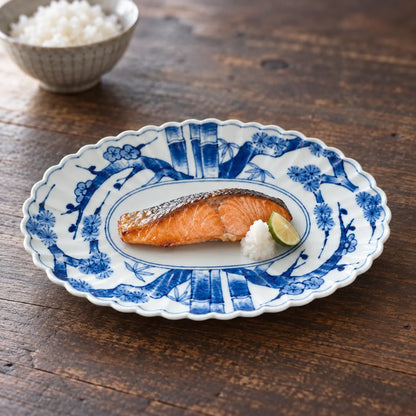 Arita pine, bamboo and plum oval porcelain platter holding a small piece of grilled salmon