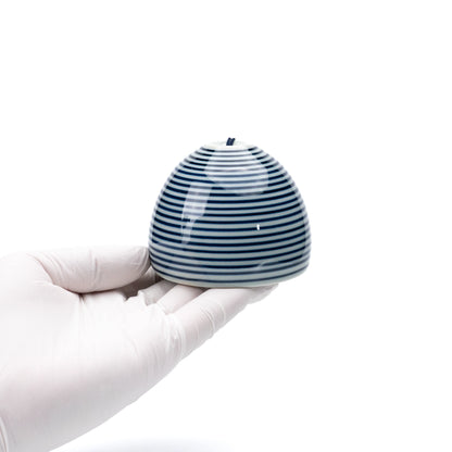 Blue striped porcelain wind chime held in a gloved hand.