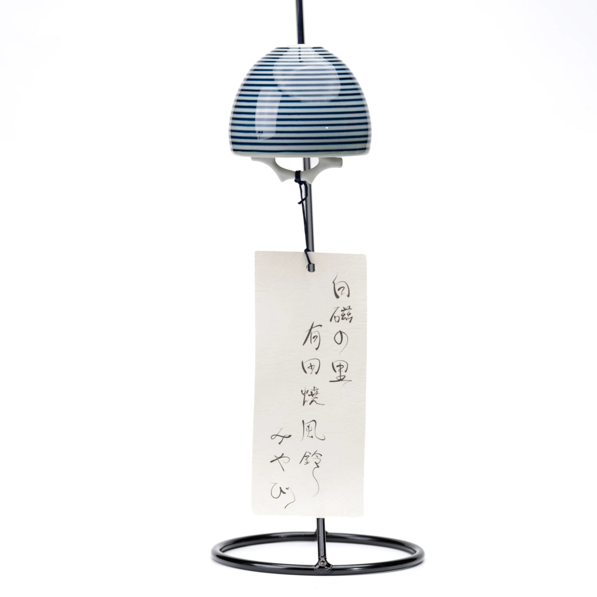 Striped porcelain wind chime and paper strip hanging from a black display stand on white.