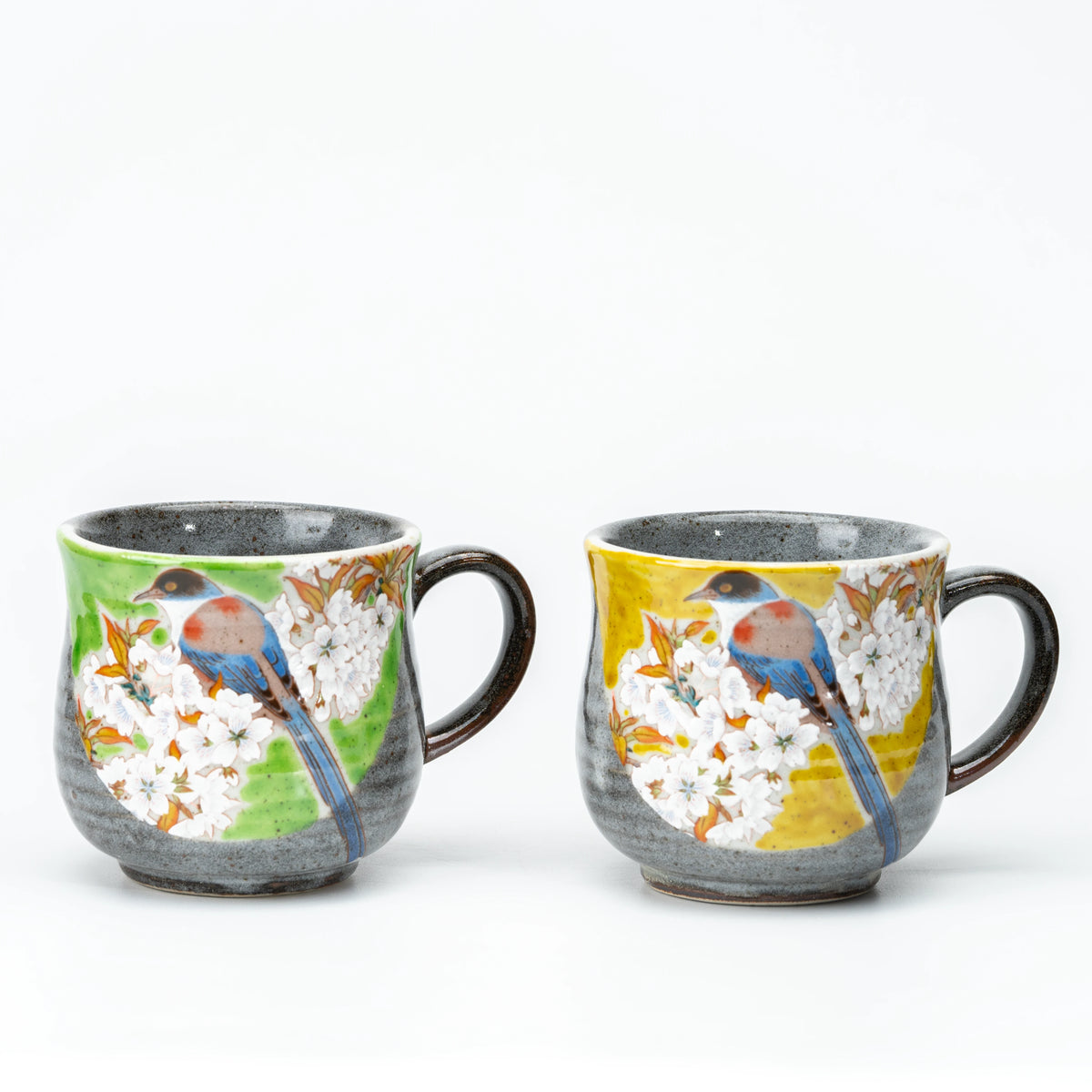 Pair of gray Kutani mugs with painted birds, white cherry blossoms and green or yellow accents.