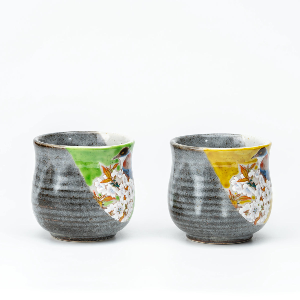 Side view of the Kutani bird mug pair showing gray glaze and colored panels.