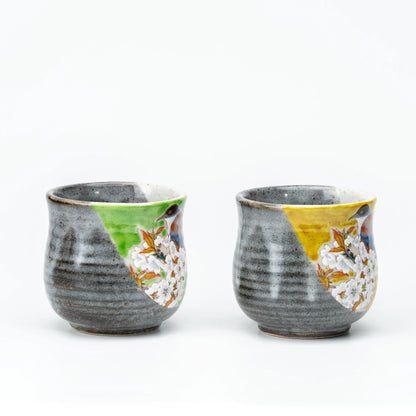 Side view of the Kutani bird mug pair showing gray glaze and colored panels.