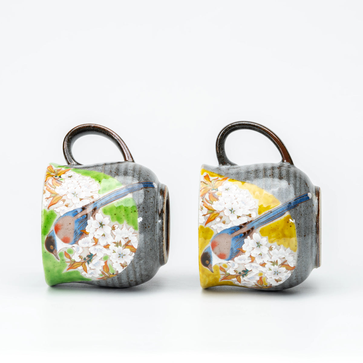 Kutani bird mug pair tilted to show their bases and painted birds.