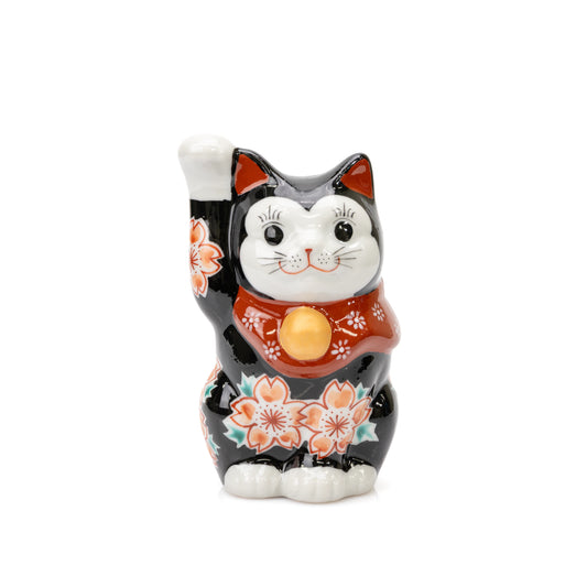 Front view of a black Kutani lucky cat with cherry blossoms, a red bib and a raised right paw.