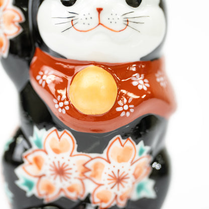 Close-up of the lucky cat's red floral bib and gold-colored bell.