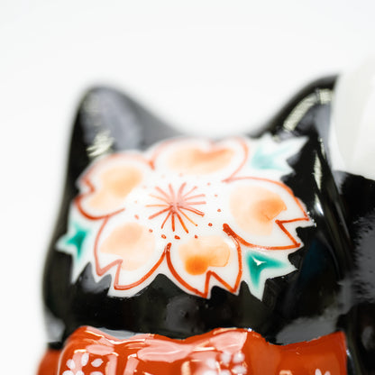 Close-up of a cherry blossom on the back of the lucky cat's head.