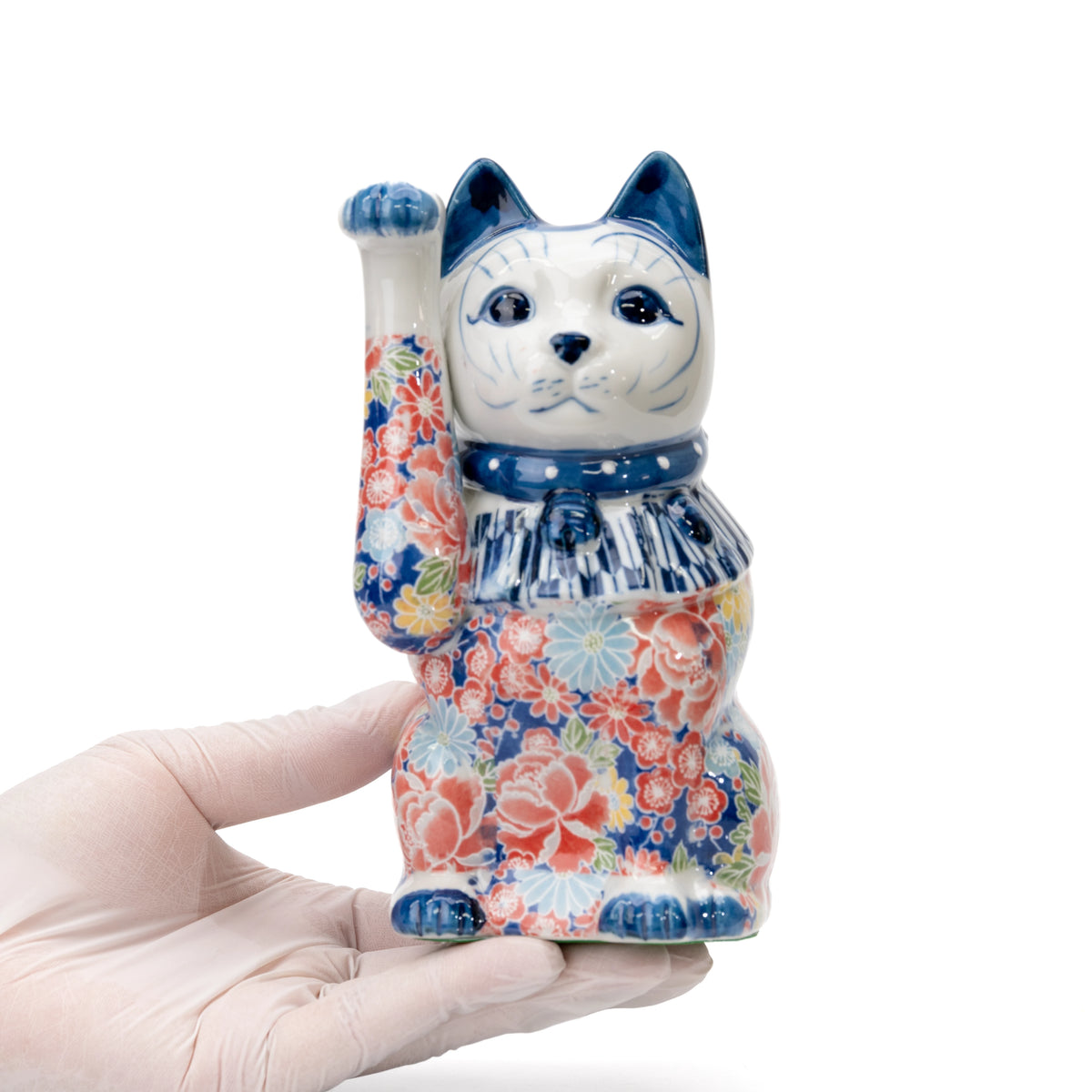 Blue floral lucky cat held in a gloved hand.
