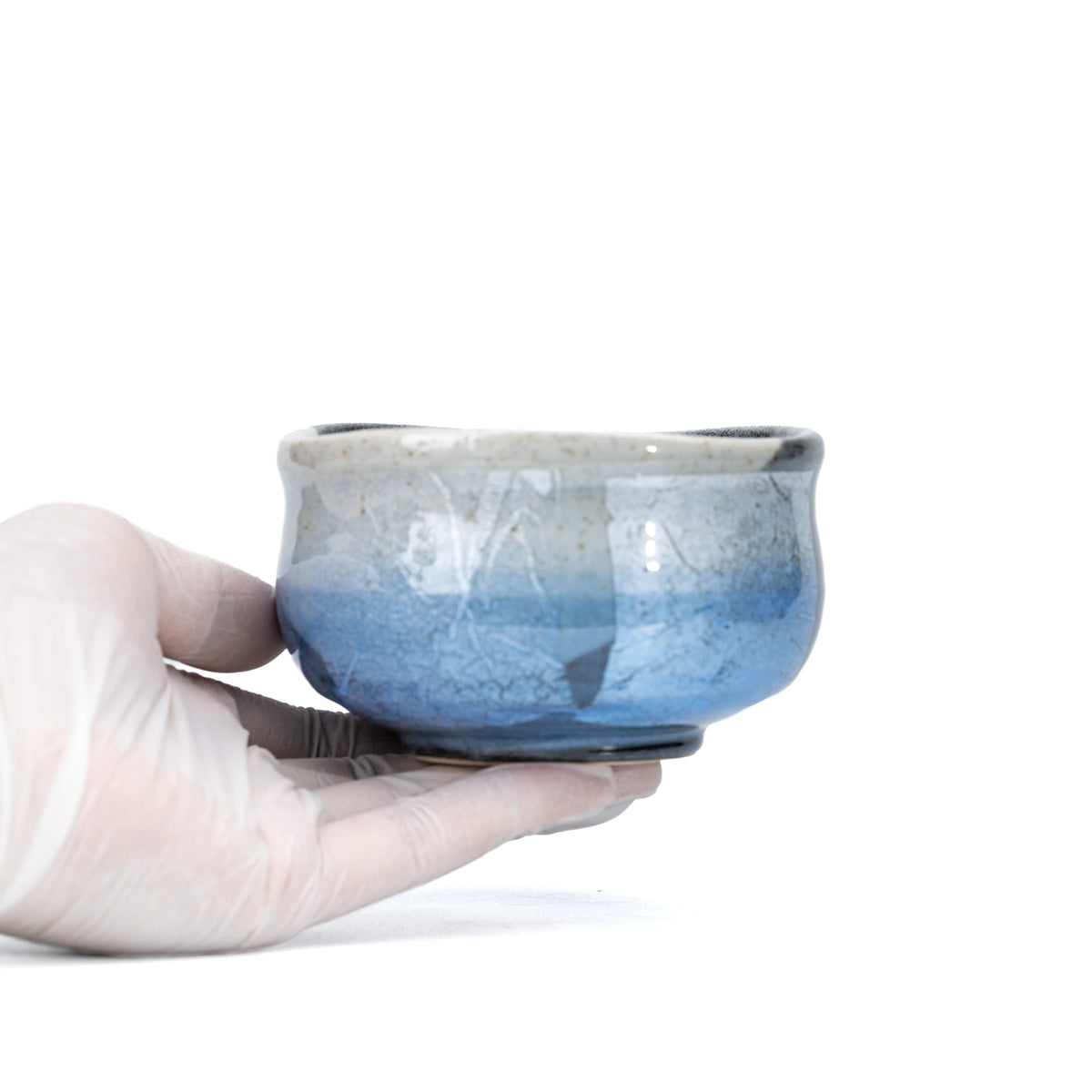 Blue ginsai matcha bowl held in a gloved hand.