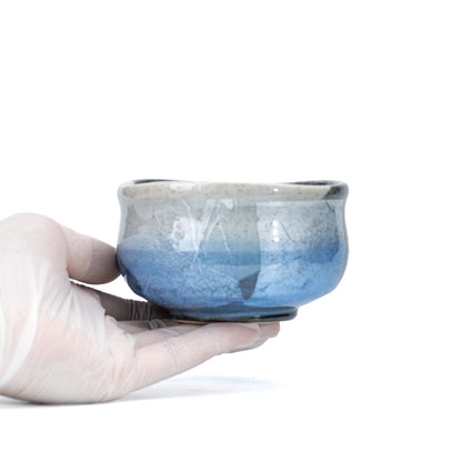 Blue ginsai matcha bowl held in a gloved hand.