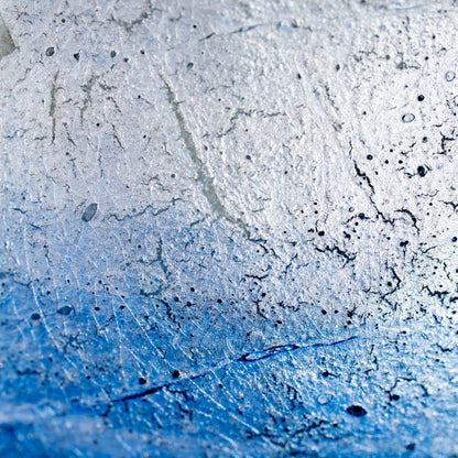 Close-up of silver-foil texture beneath pale blue glaze.