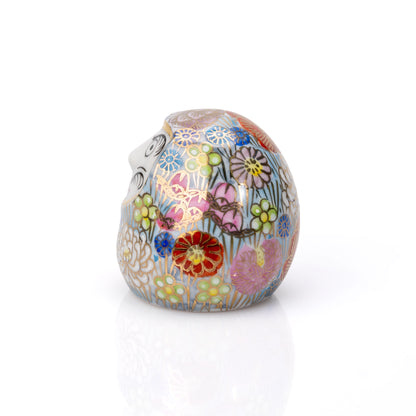 Back of the rounded daruma with dense multicolored floral decoration.