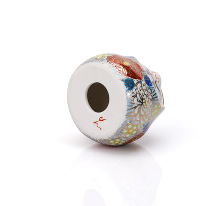 Underside of the floral daruma with a round opening and red inscription.