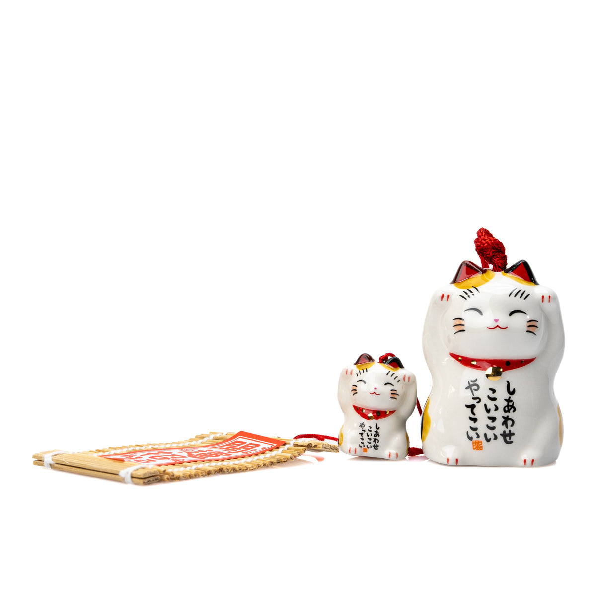 Cat and kitten wind chime resting on white with its paper strip extended.