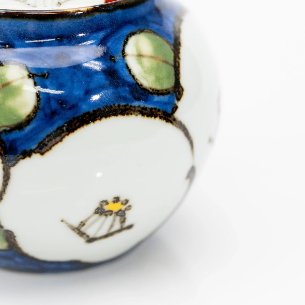 Close-up of a white camellia with yellow and dark stamens against the teapot’s blue glaze.