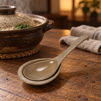 Ginpo Hana Mishima ceramic serving spoon resting on its matching dish beside a hot pot