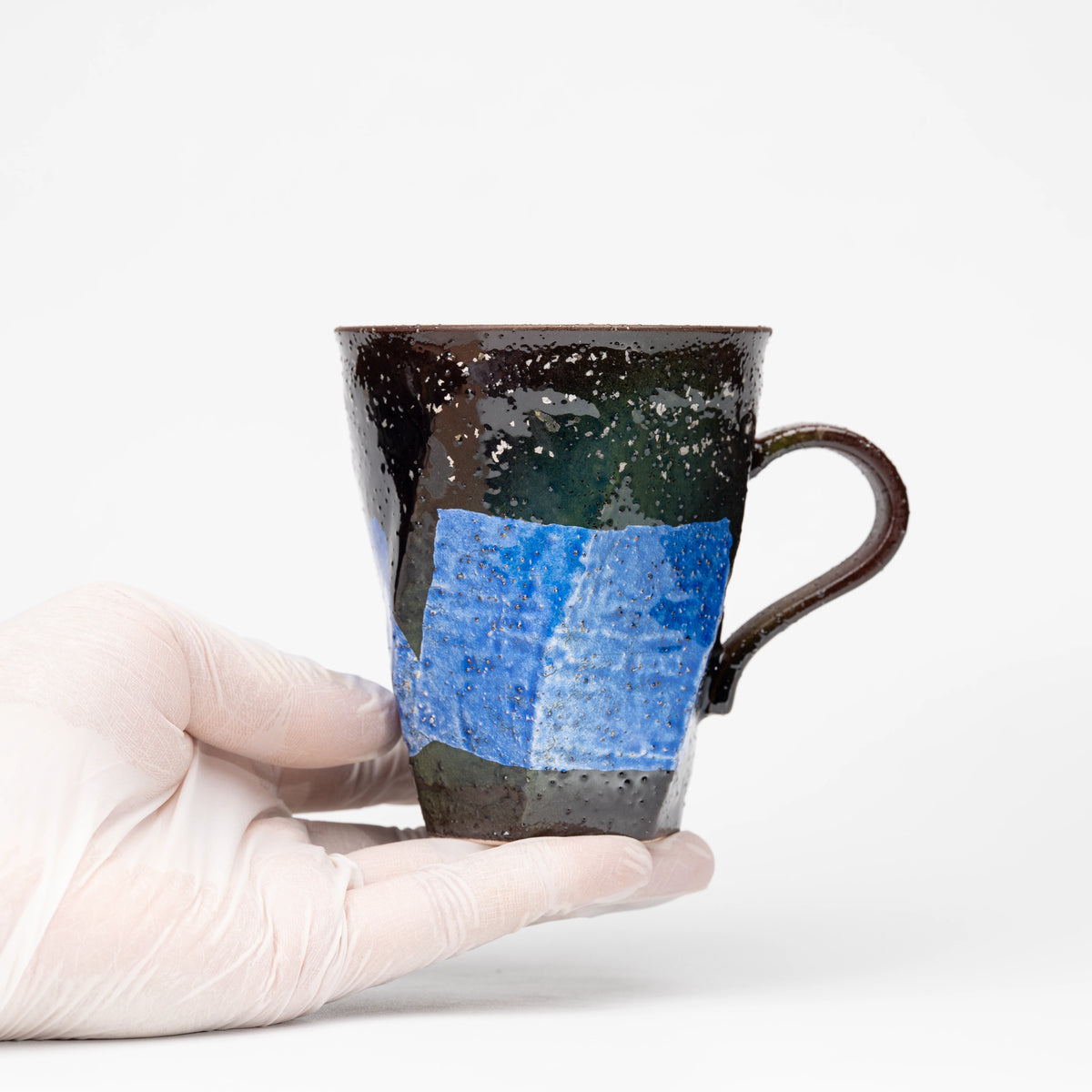 Blue ginsai mug held in a gloved hand.