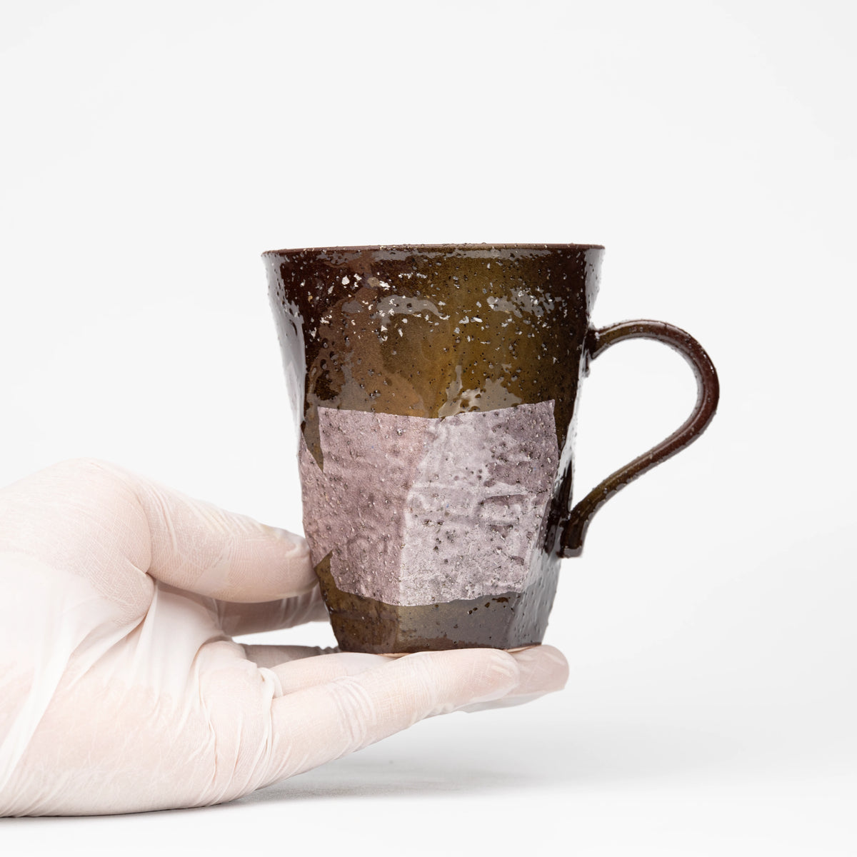 Lilac ginsai mug held in a gloved hand.