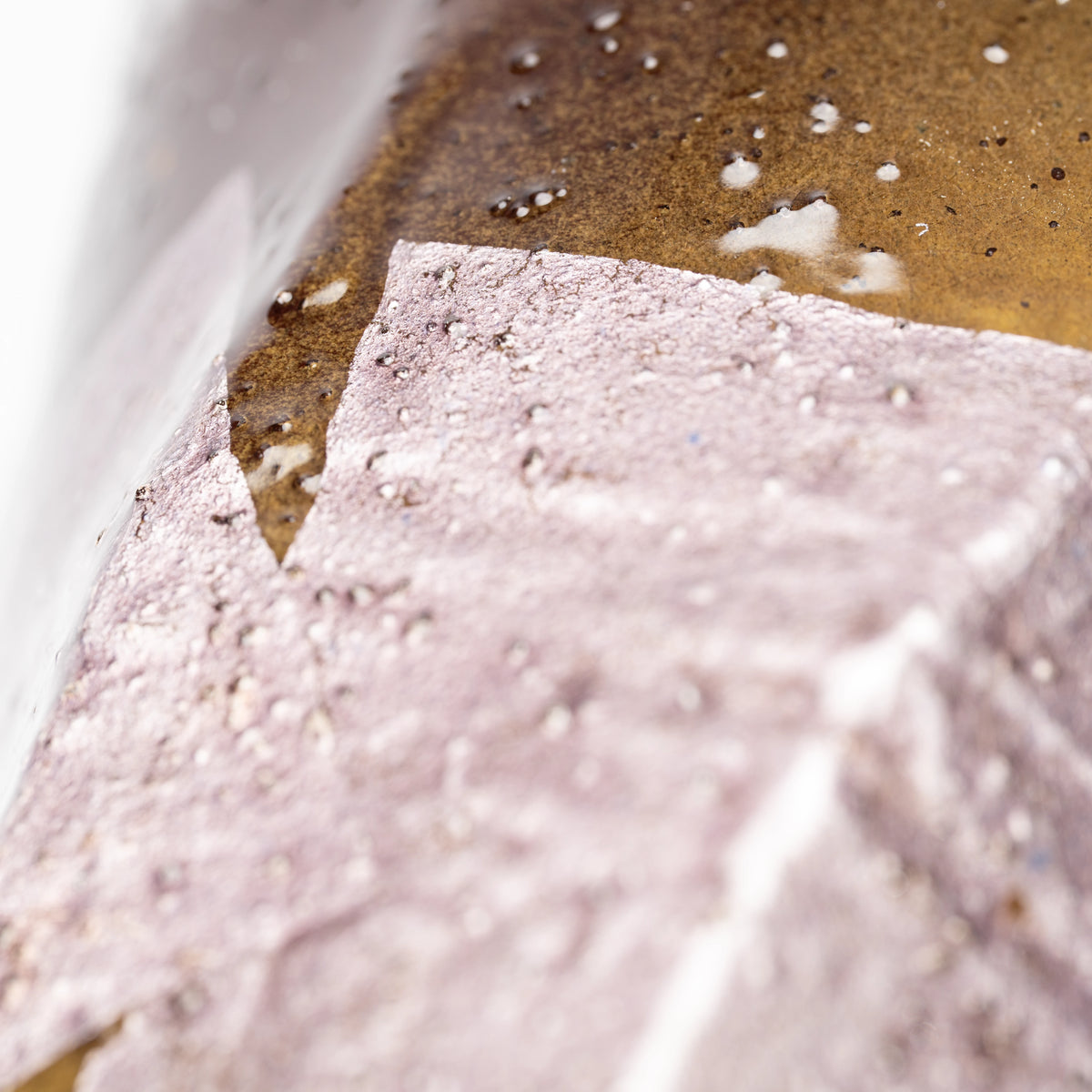Close-up of a pale lilac silver-foil panel and warm brown glaze.