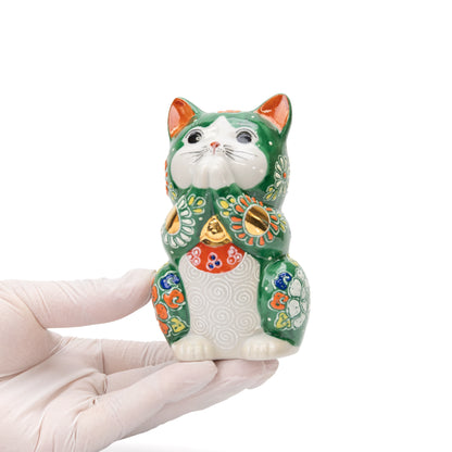 Green floral praying cat held in a gloved hand.