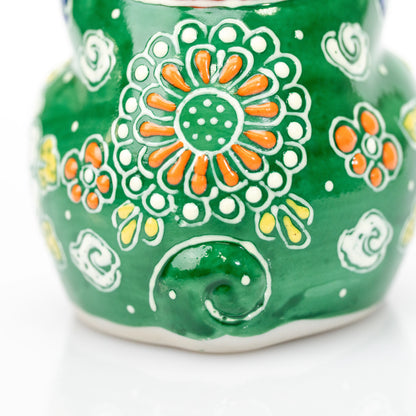Raised floral decoration and curled tail on the cat's green back.
