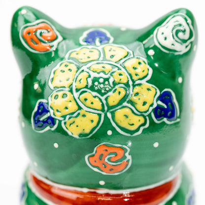 Yellow and blue flower painted on the back of the green cat's head.