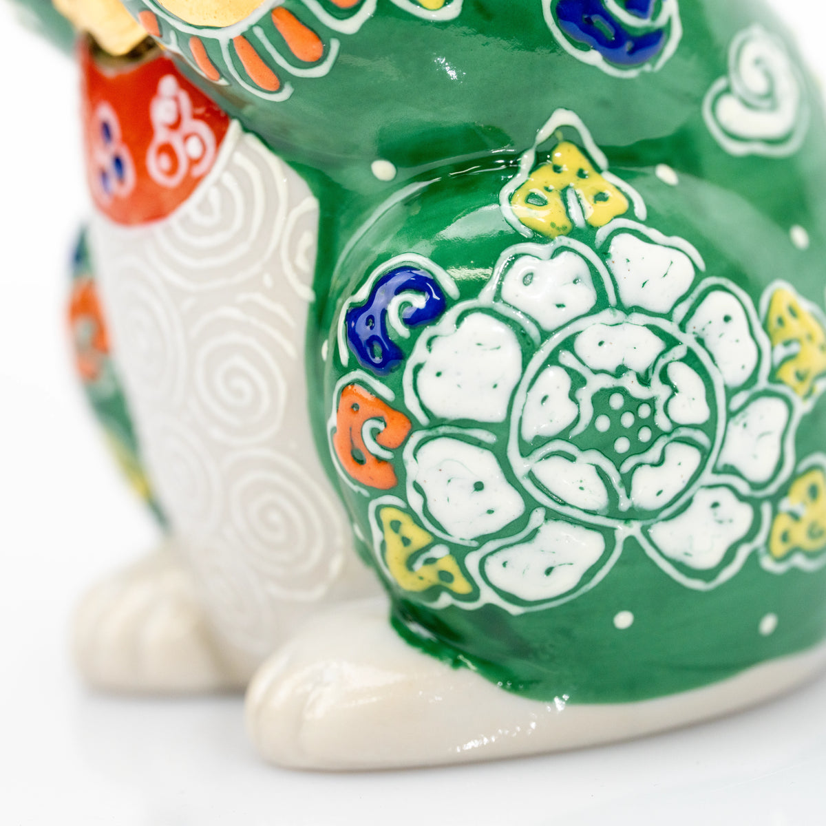 Close-up of the green cat's white feet and raised white flower.