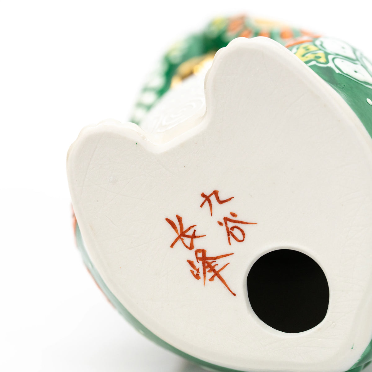 Red maker's inscription and round opening on the underside of the green cat.