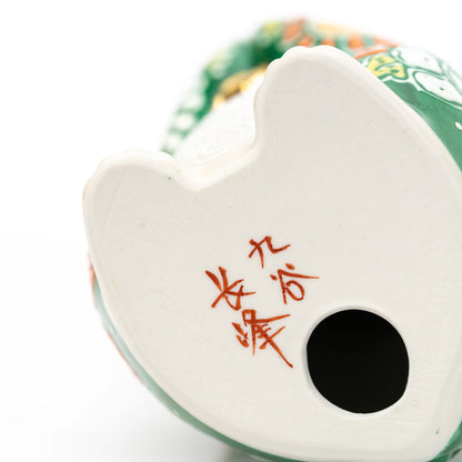 Red maker's inscription and round opening on the underside of the green cat.