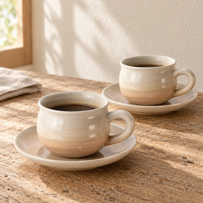 Two blush-glazed Hagi Himetsuchi coffee cups on their matching saucers in warm morning light.