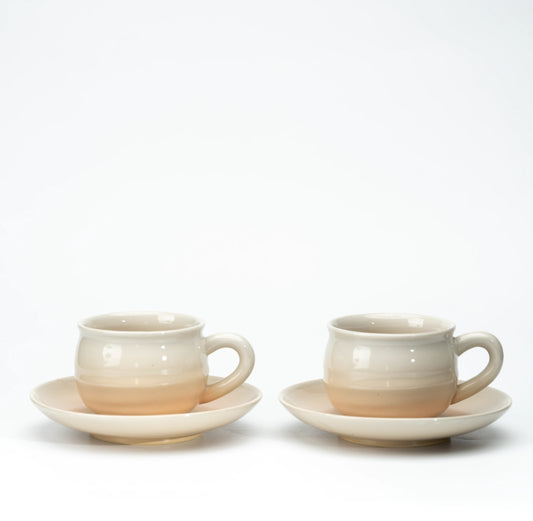 Two Hagi pottery cups and matching saucers with cream and warm beige glaze on white.