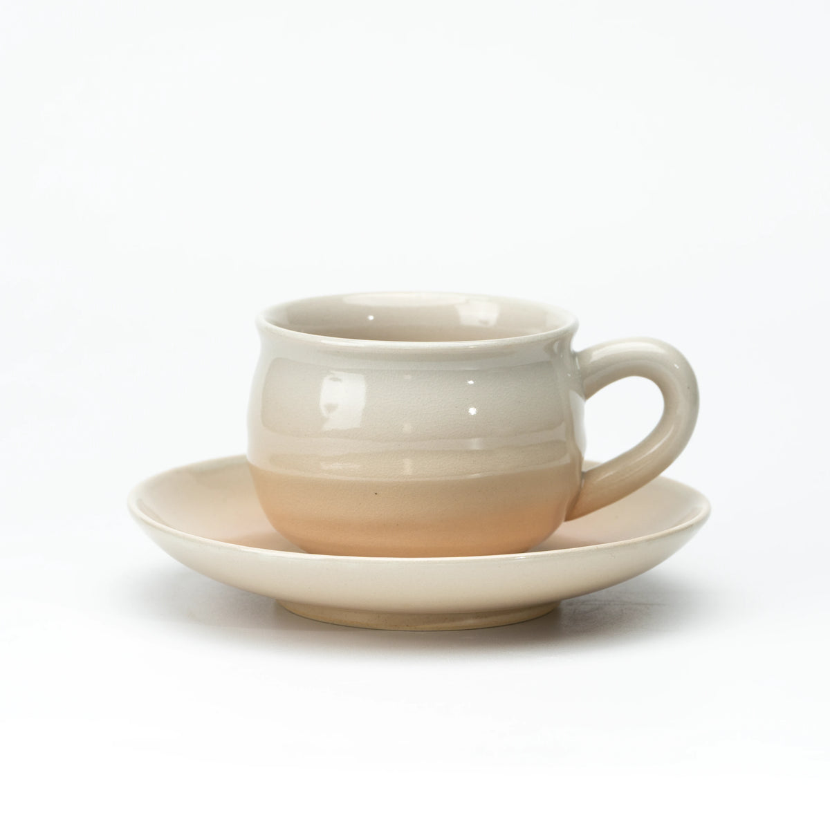 Side view of a cream and beige Hagi cup and saucer.