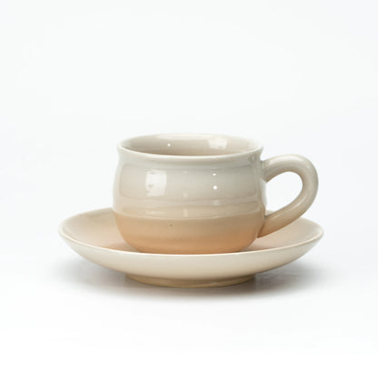 Side view of a cream and beige Hagi cup and saucer.