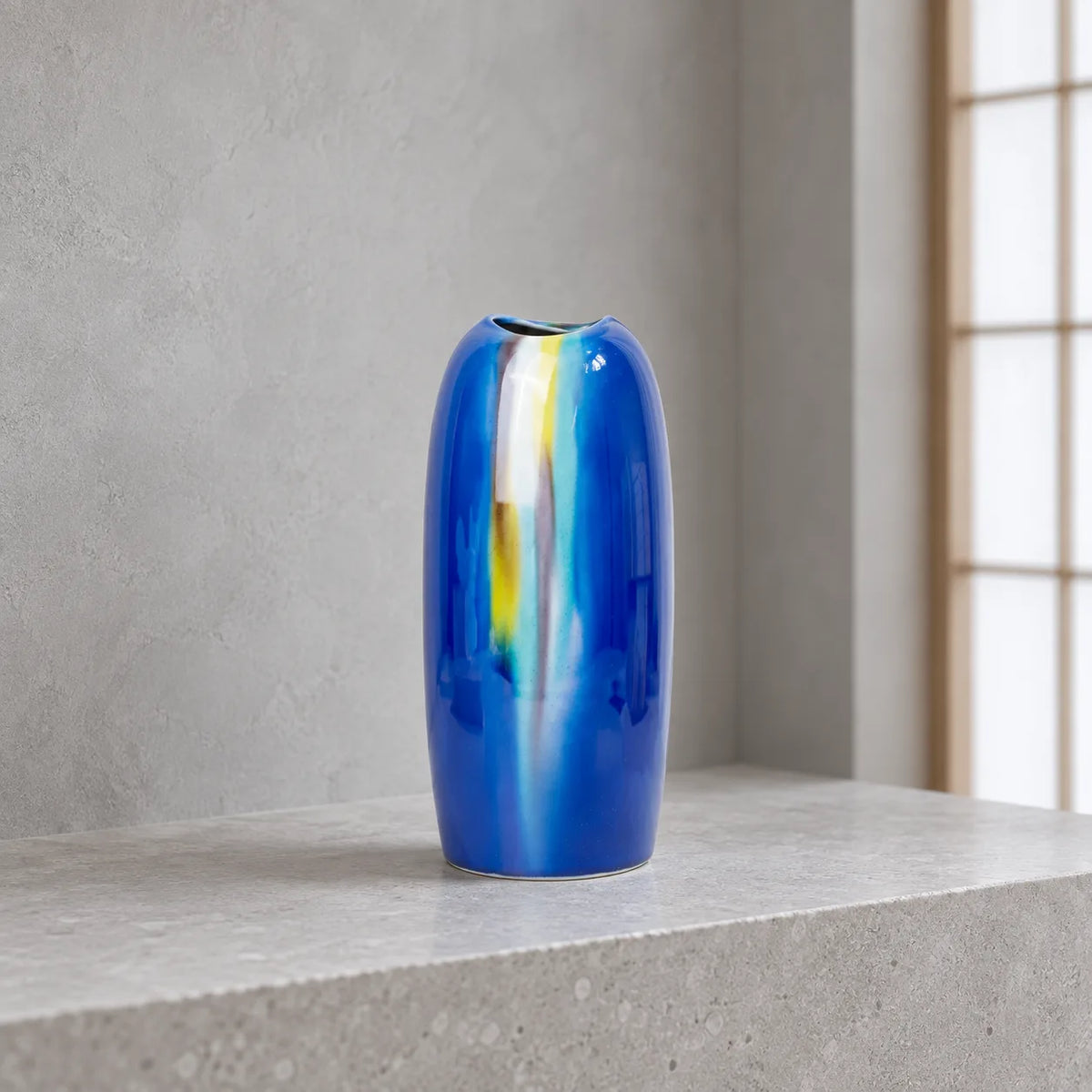 Vase Yusai bleu Hakuho en porcelaine de Kutani, présenté vide sur un rebord en pierre claire, dans une lumière du jour douce et froide.