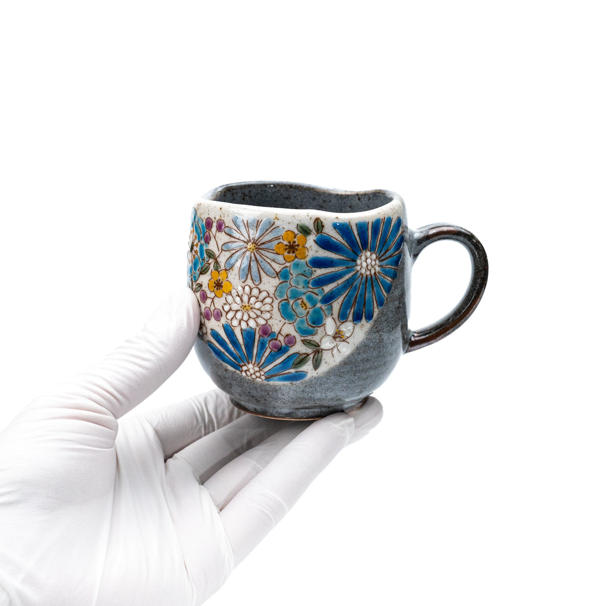 Blue floral Kutani mug held in a gloved hand to show scale.