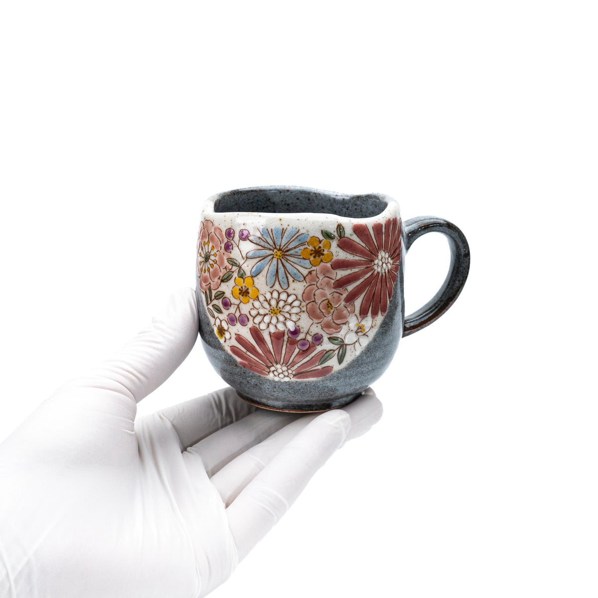 Red floral Kutani mug held in a gloved hand to show scale.