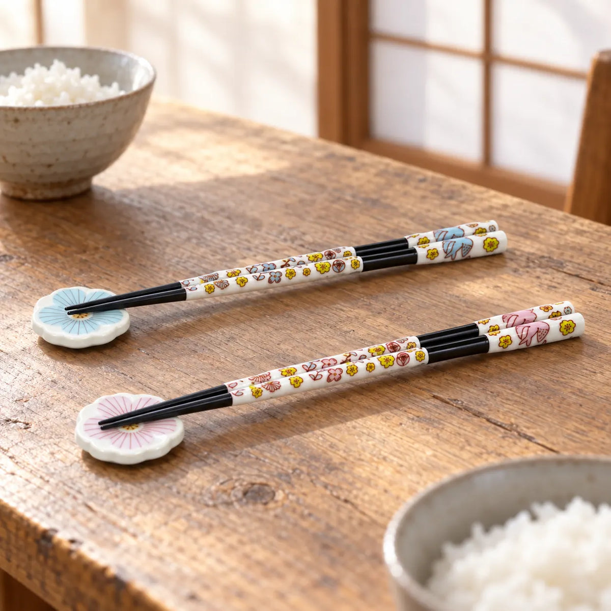 Two pairs of Harekutani chopsticks on matching blue and pink porcelain flower rests at a breakfast table