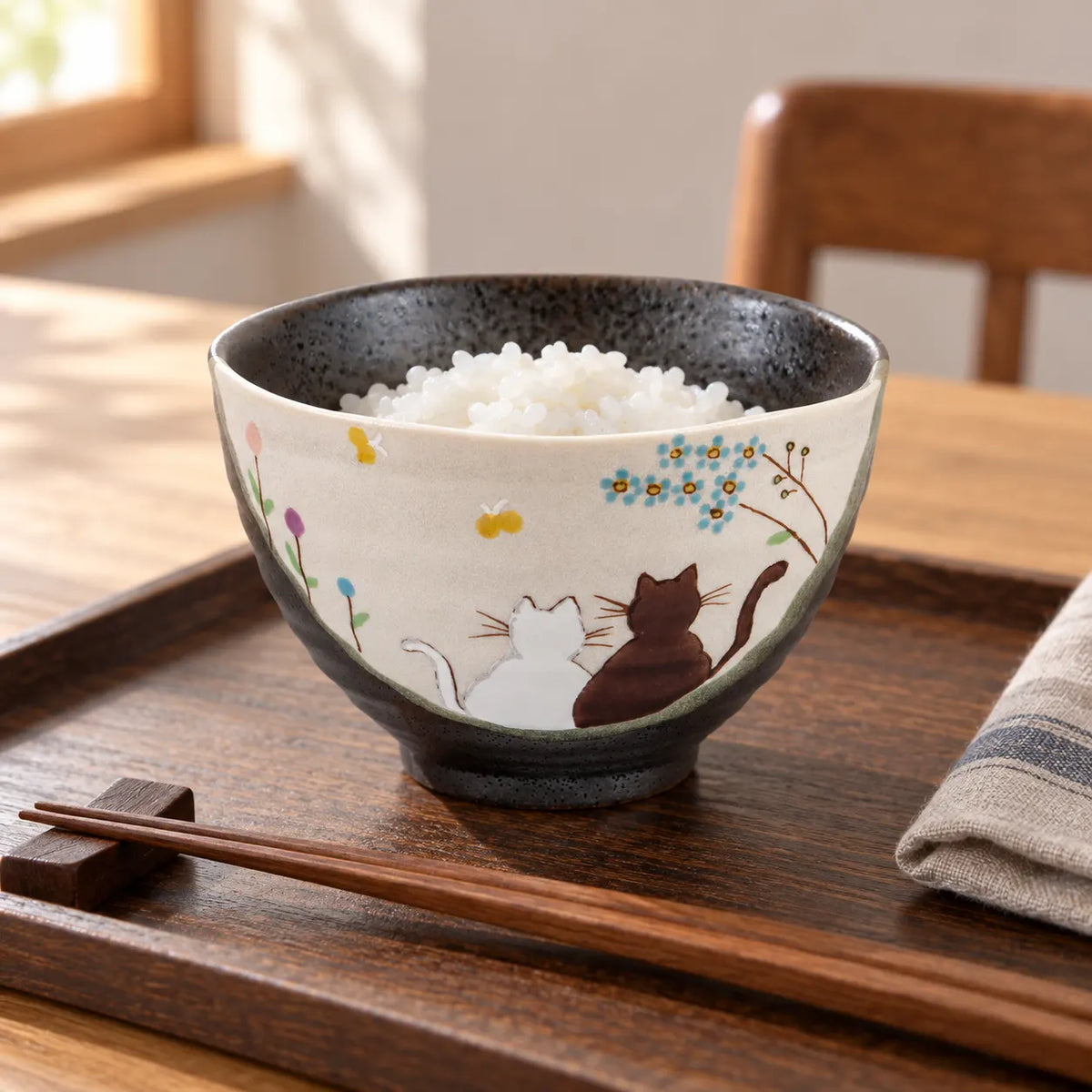 Kutani Hidamari cat bowl with a small serving of white rice on a wooden breakfast tray, showing two painted cats