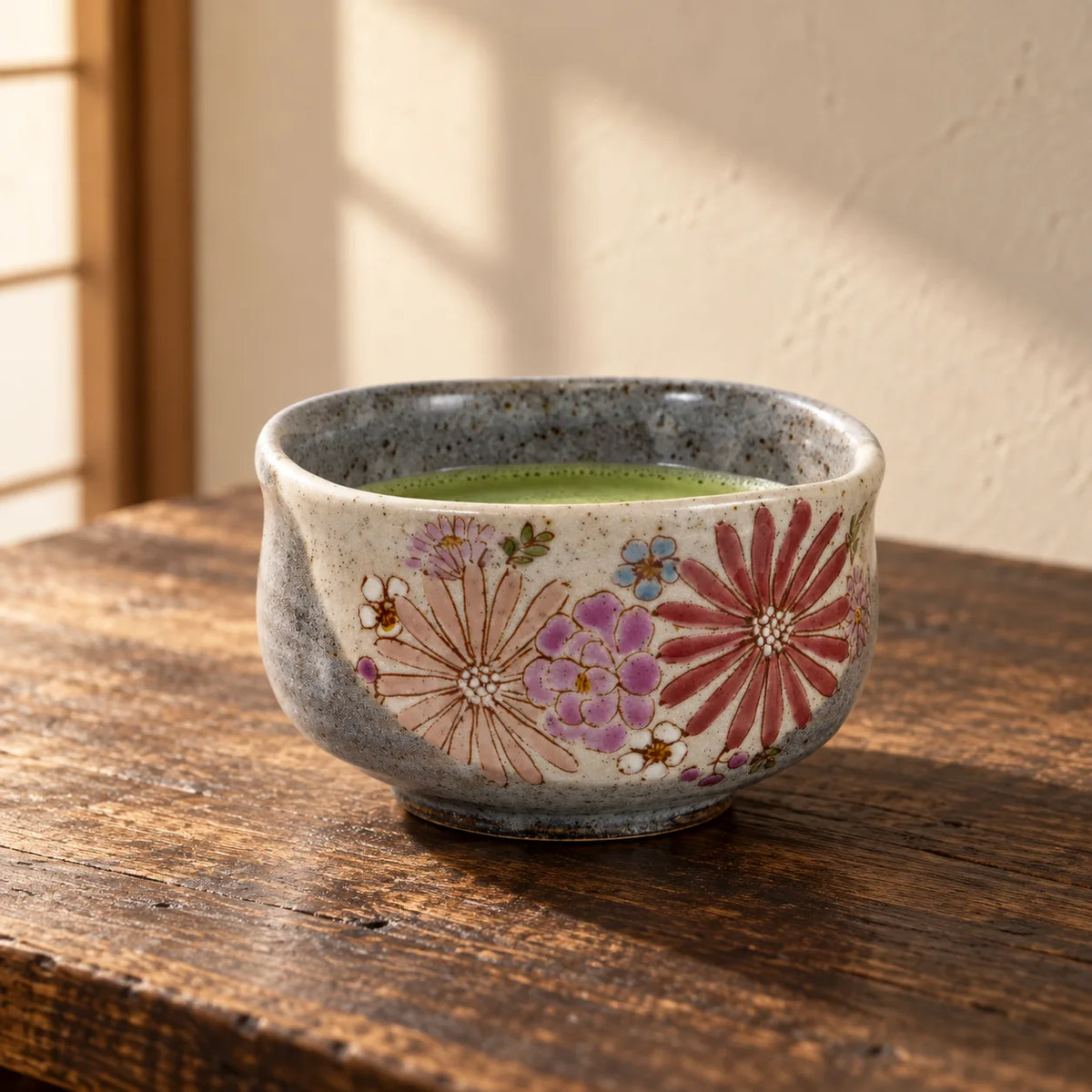 Bol à matcha Iroe Yu Hana, contenant un fond de matcha, sur une table en bois aux tons chaleureux.