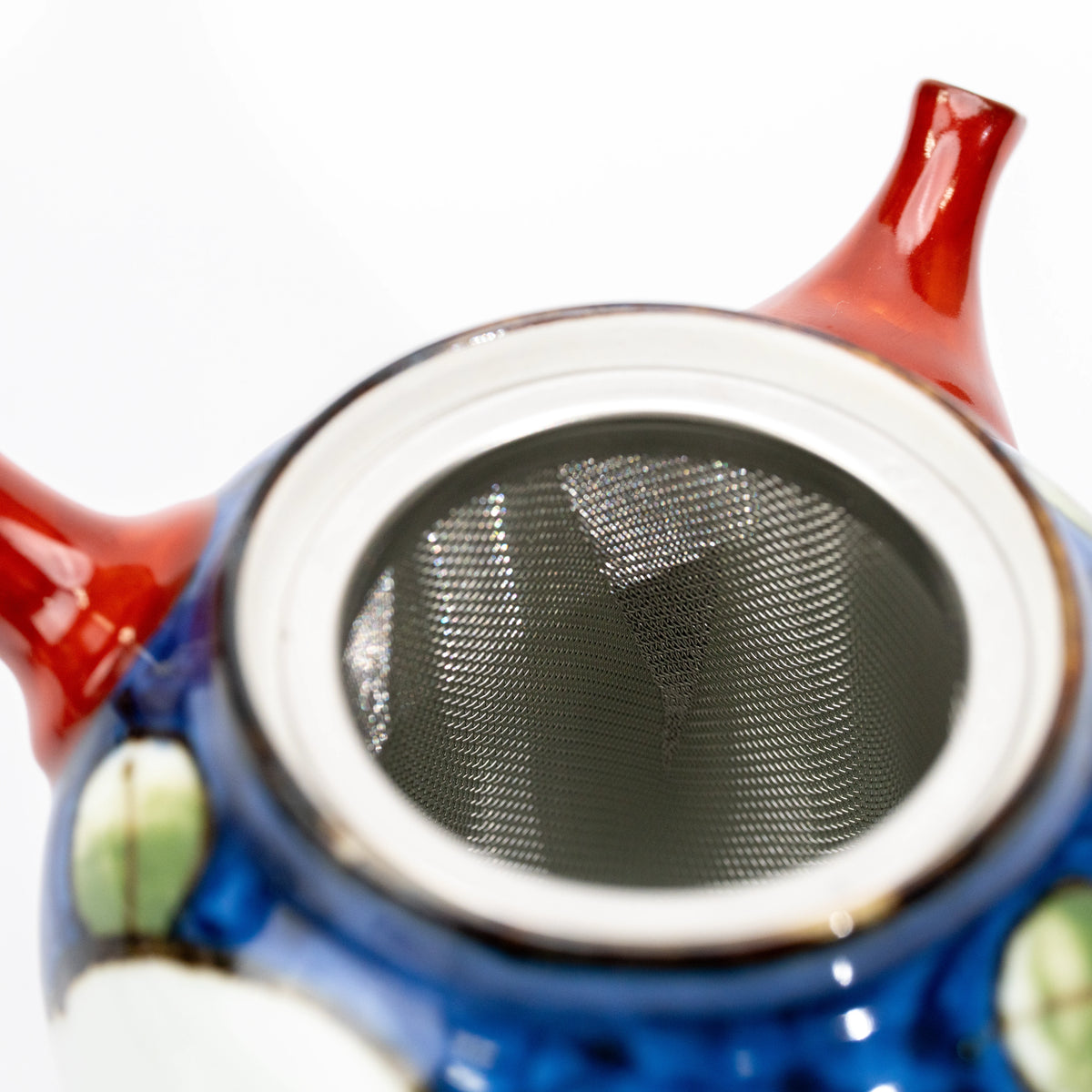 Metal tea strainer inside the open camellia teapot.