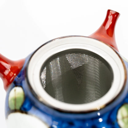 Metal tea strainer inside the open camellia teapot.