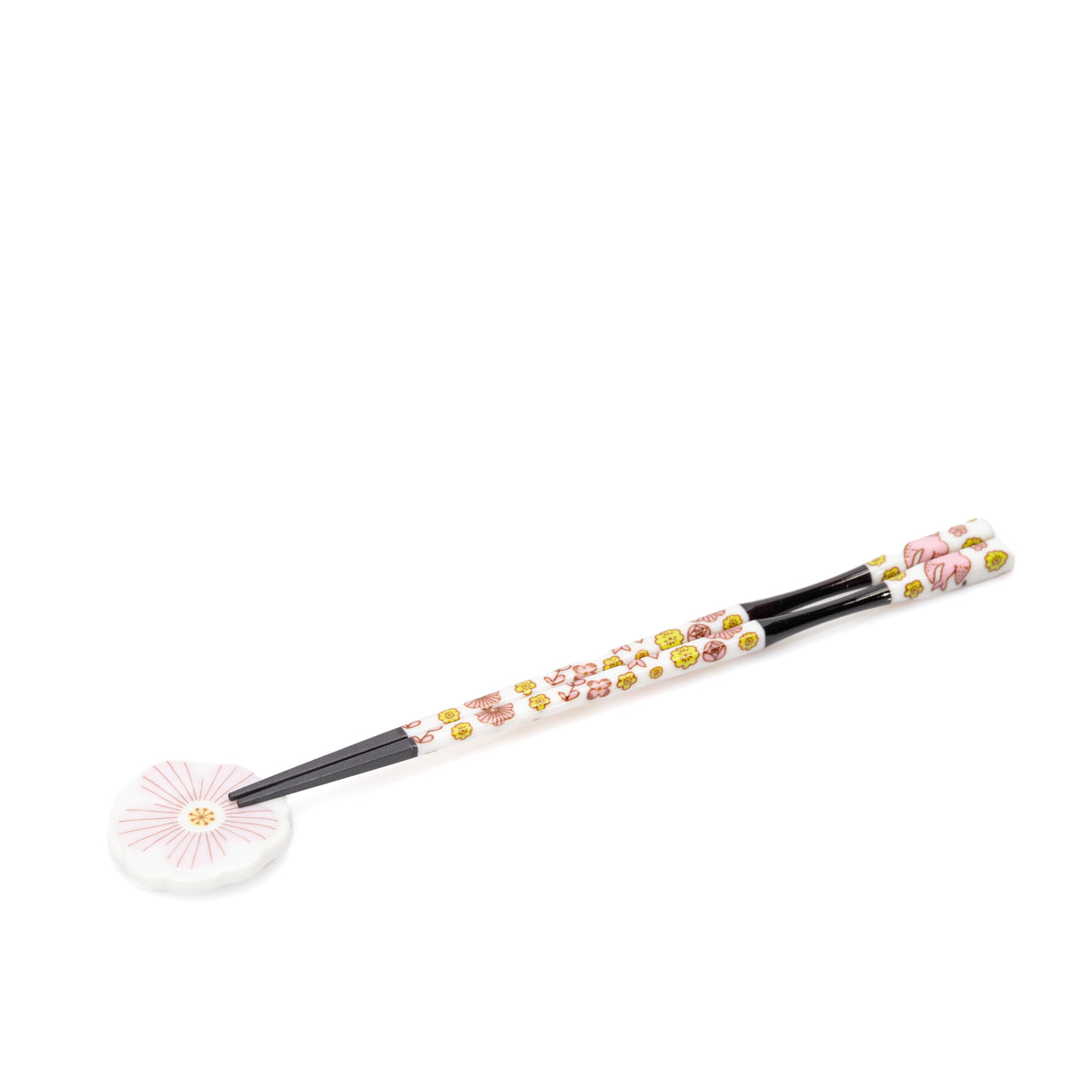Black chopsticks with floral handles on a pink porcelain rest.